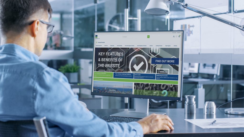 Automotive Engineer Working on a Personal Computer With Isolated Mock-up Green Screen on it. He Works in the Bright and Modern Office with Car Sketches on the Walls.